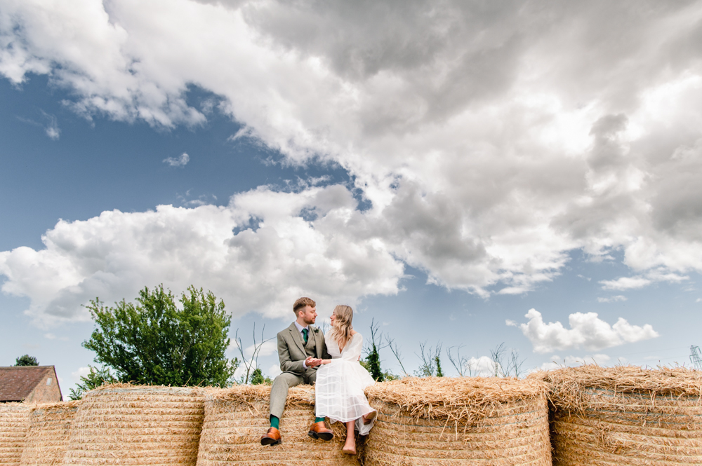 bride and groom on haybales wedding cotswolds